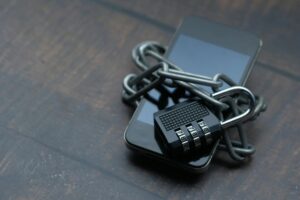 Close-up of a smartphone wrapped in a chain with a padlock, symbolizing strong security.