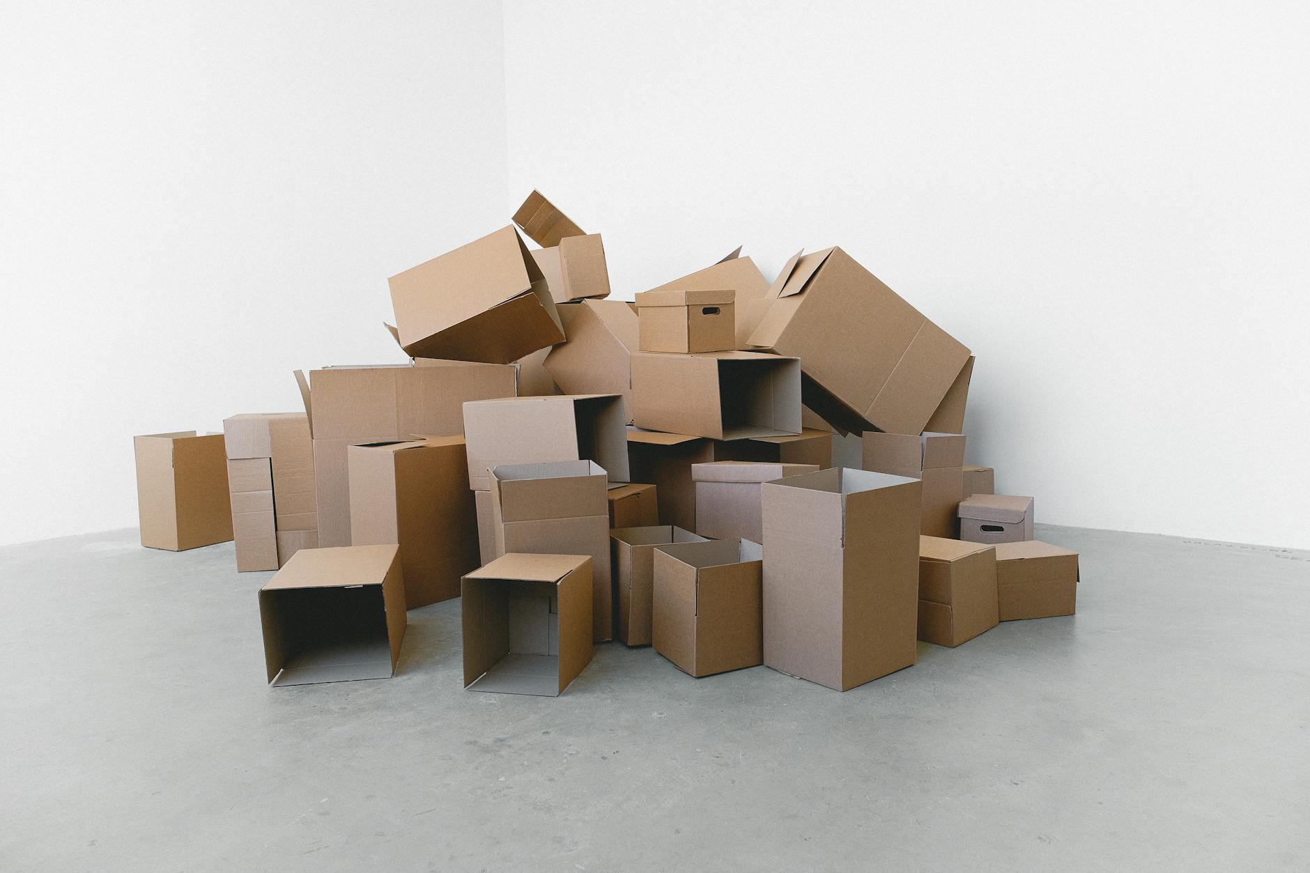 Pile of cardboard containers prepared for relocation on floor at home in daylight on white background
