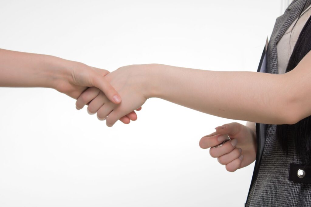 An up-close image of two people shaking hands in a professional setting against a white background.